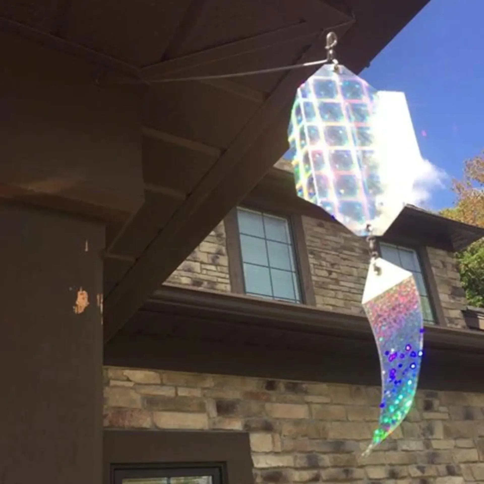 Michigan Wildlife Solutions - A wind spinner is hanging from the roof of a house.