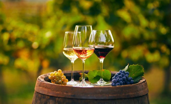 Three glasses of white, rose and red wine on a wooden barrel