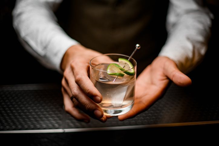 Close-up on hands of man bartender holding glass with cold drink