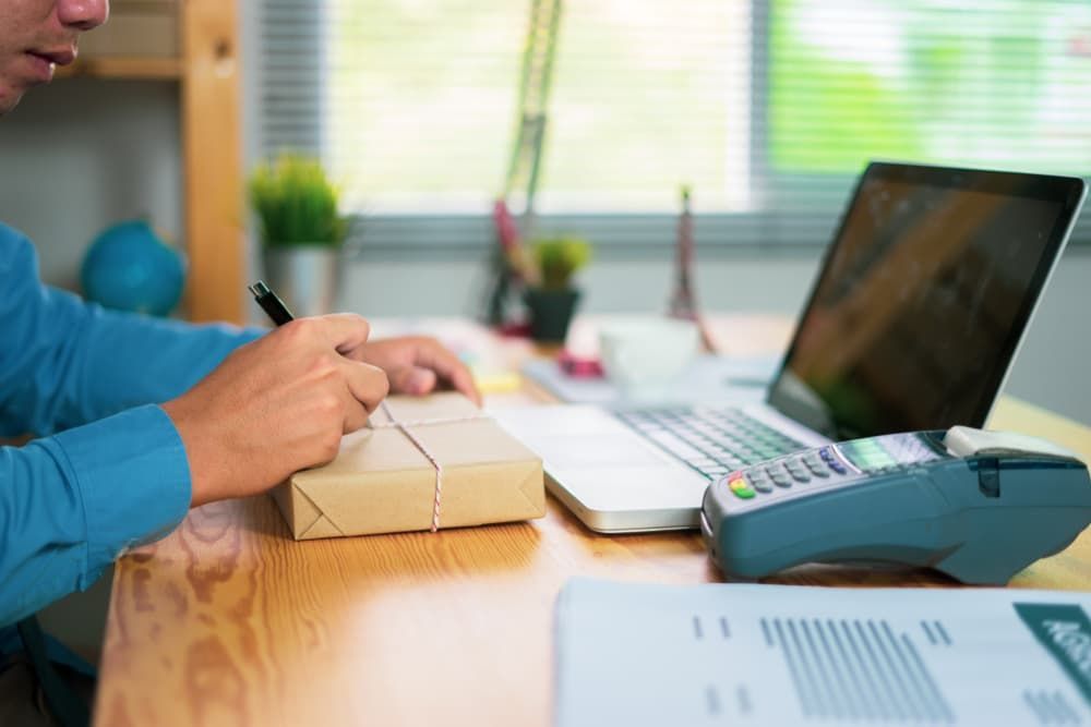 A Person in a Blue Long-sleeved Shirt Writes on a Small Package — Richardson Conveyancing In Tumbi Umbi, NSW