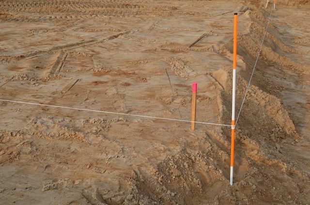A Construction Site Features a Survey Pole and a Wooden Stake With Pink Ribbon — Richardson Conveyancing In Tumbi Umbi, NSW