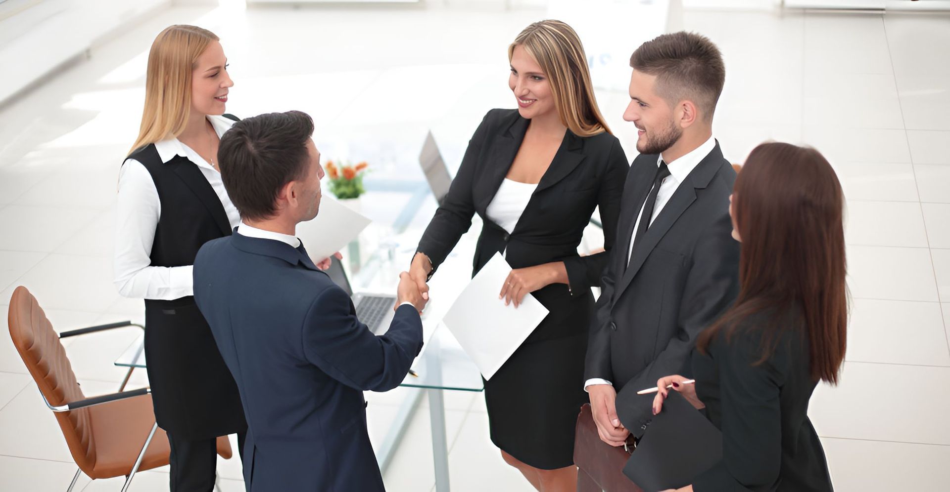 Four Professionals in Business Attire Shaking Hands in a Bright — Richardson Conveyancing In Tumbi Umbi, NSW