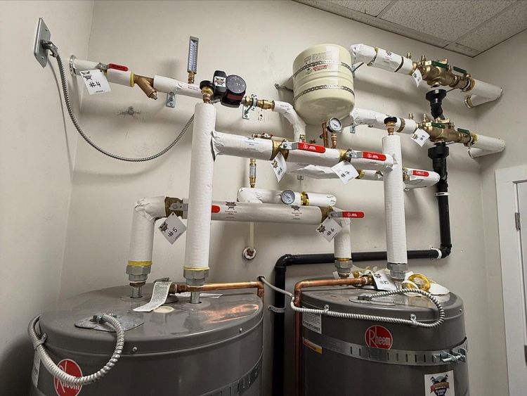 Commercial plumbing and water filtration setup with pipes, valves, and two large tanks in a utility room