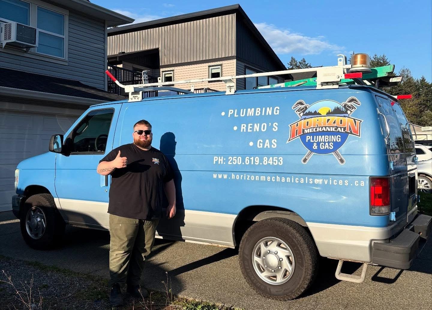 Man standing beside a blue plumbing service van parked on a street.