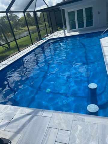 Backyard swimming pool with blue water, screened enclosure, and patio beside a house