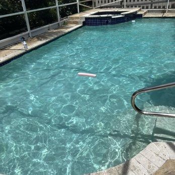 Backyard swimming pool with clear blue water, a pink float, and metal handrails on the steps