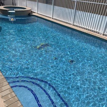 Backyard swimming pool with blue water, circular spa, and white fence along the side