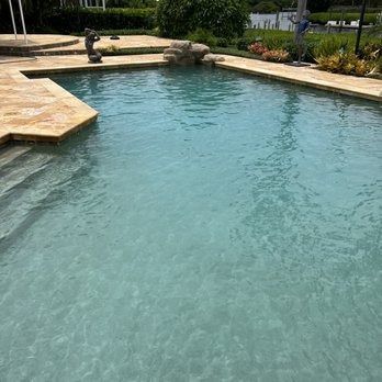 Backyard swimming pool with clear blue water, stone deck, and landscaped garden surround