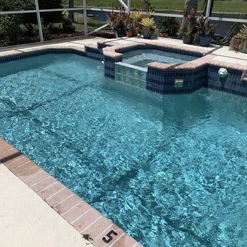 Clear blue backyard swimming pool with tiled spa and deck seating area