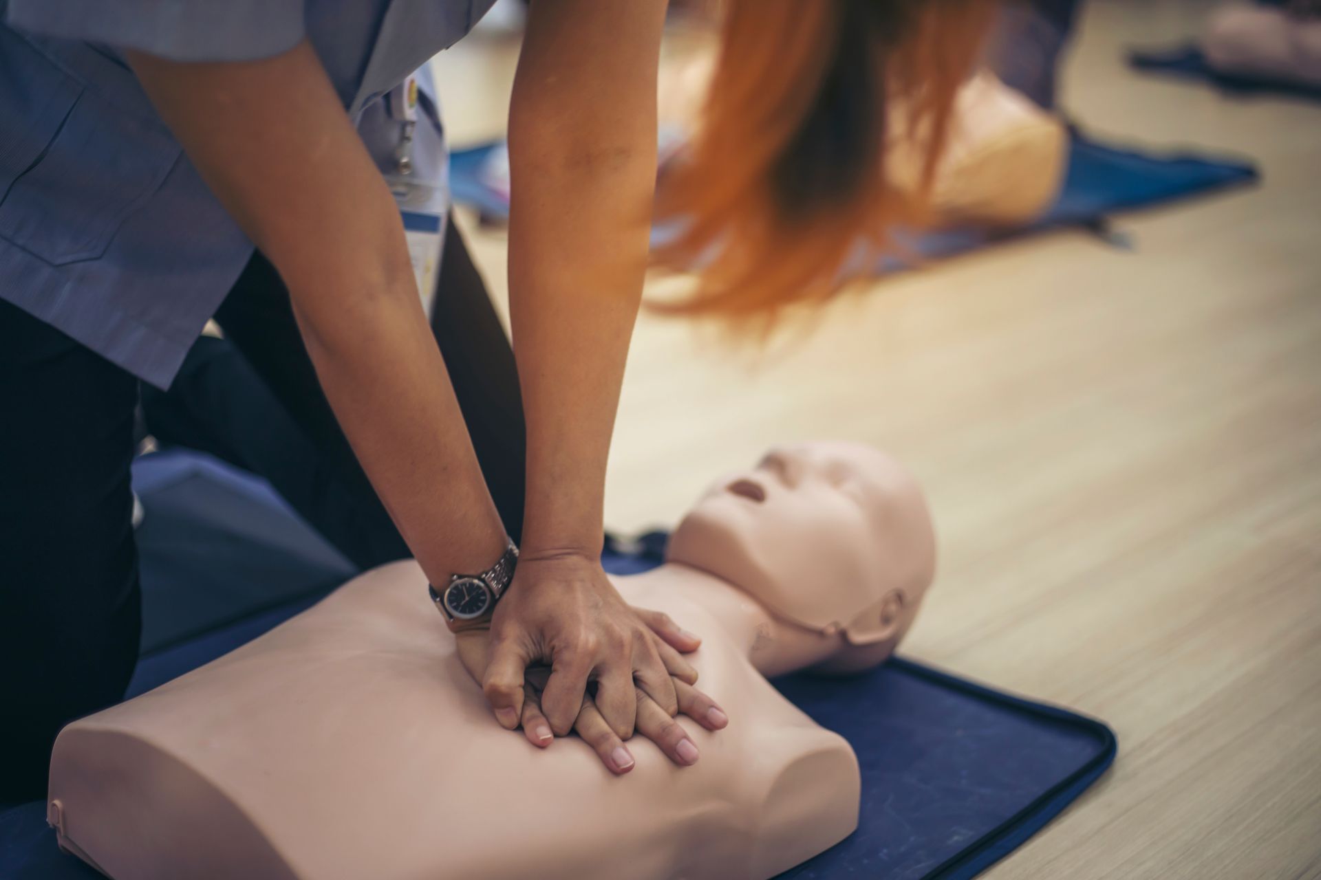 Person performing CPR on a training dummy during a first aid class.