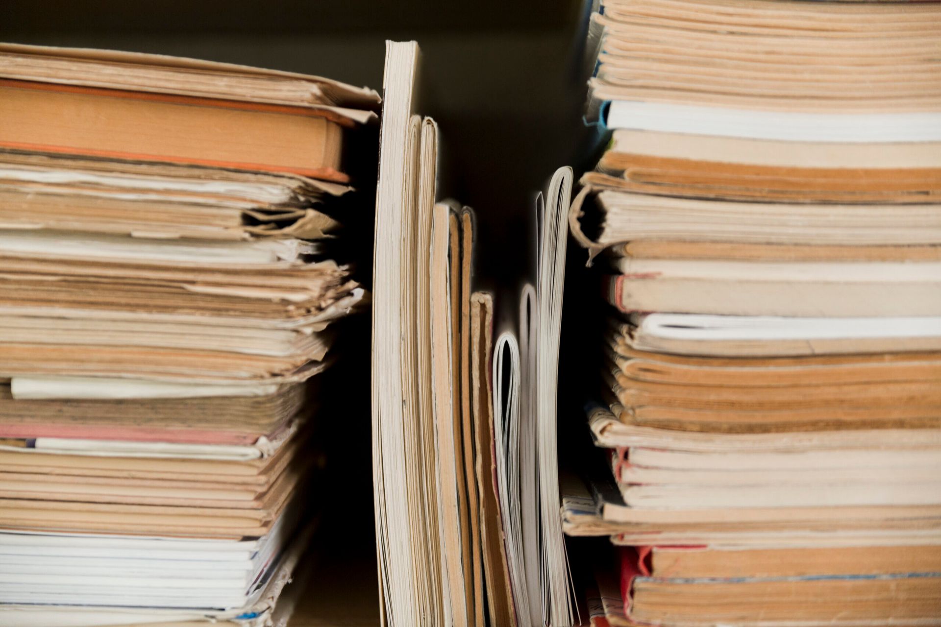 Stacks of old books on a shelf, pages yellowed, with a narrow space between them.