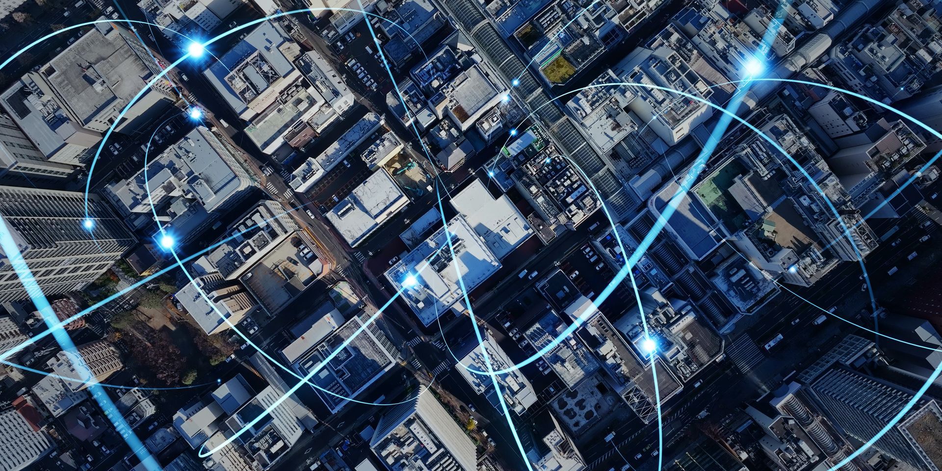 Overhead view of a city with connected blue lines and glowing nodes, representing data networks. Overhead view of a city with connected blue lines and glowing nodes, representing data networks.