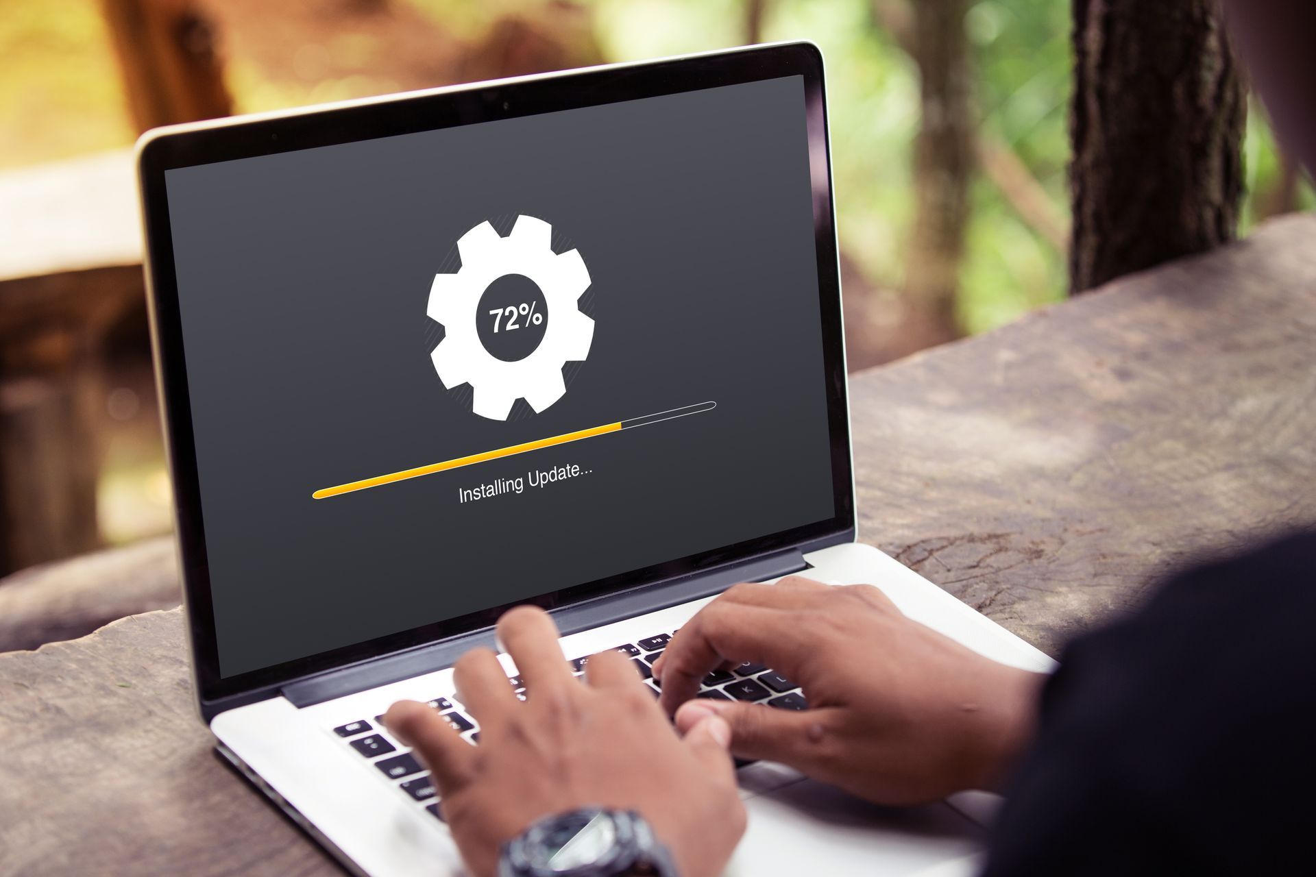 Person using a laptop outdoors, displaying a software update screen. Person using a laptop outdoors, displaying a software update screen.