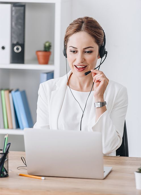 A woman wearing a headset is sitting in front of a laptop computer.