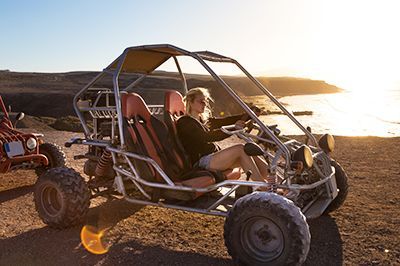 A woman is sitting in a buggy on the beach.