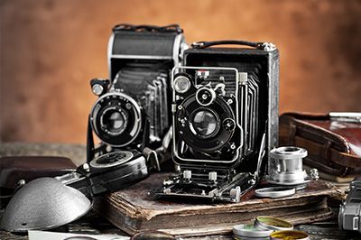 Two old cameras are sitting on top of a book on a table.