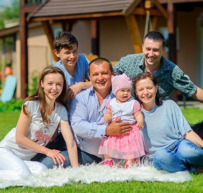 A family is posing for a picture while sitting on a blanket in the grass.