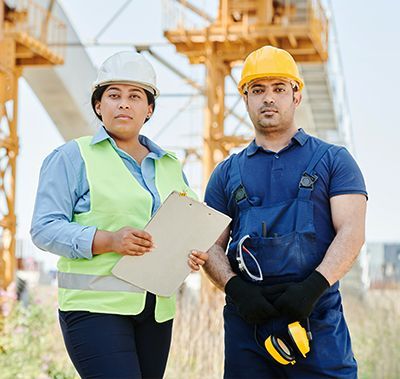 A man and a woman are standing next to each other on a construction site.