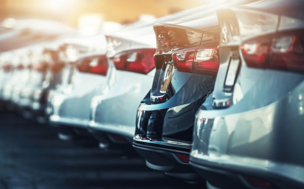 A row of silver cars parked in a lot, viewed from the rear, with lens flare from the sun in the background. — Murwillumbah Motor Wreckers in South Murwillumbah, NSW