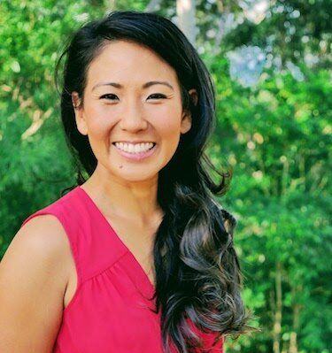 A woman in a red shirt is smiling for the camera.