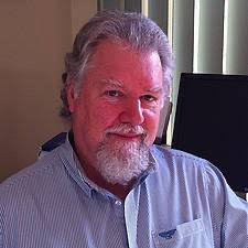 A man with a beard is sitting in front of a computer screen.
