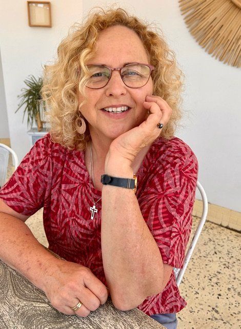 A woman wearing glasses and a red shirt is sitting at a table.
