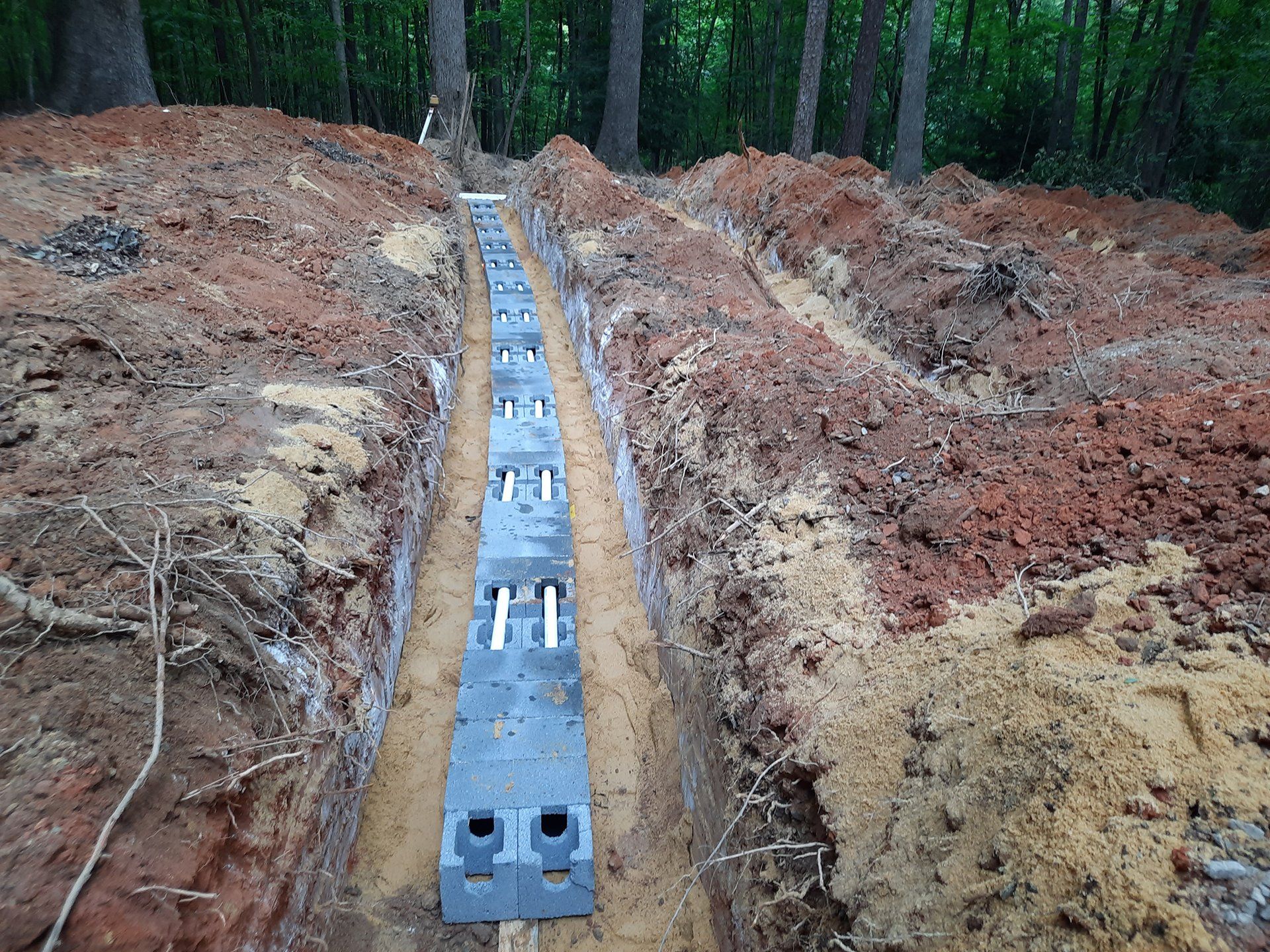 Concrete foundation trench with rebar footings in a wooded construction site