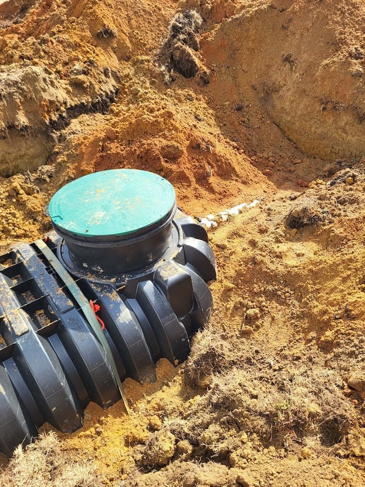 Black underground pipe with turquoise cap installed in a dirt trench