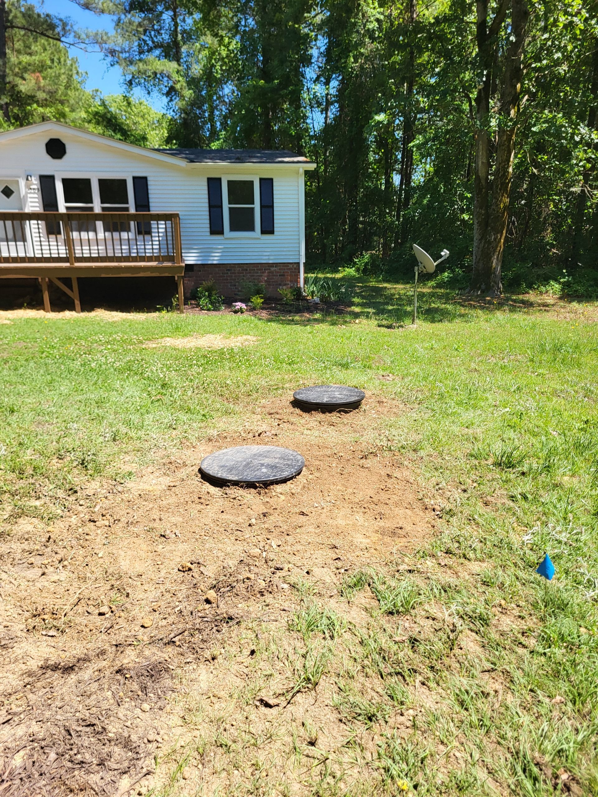 House exterior with a wooden deck and a grassy yard with two round stepping stones