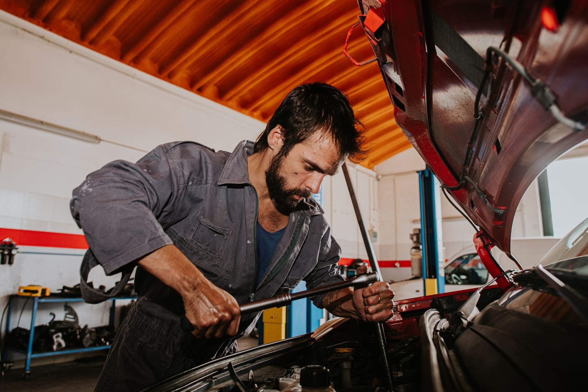 Mechanic in a garage using a wrench to work on a car engine.