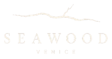Logo di Seaweed Venice in beige chiaro su sfondo bianco con una linea ondulata stilizzata sopra.