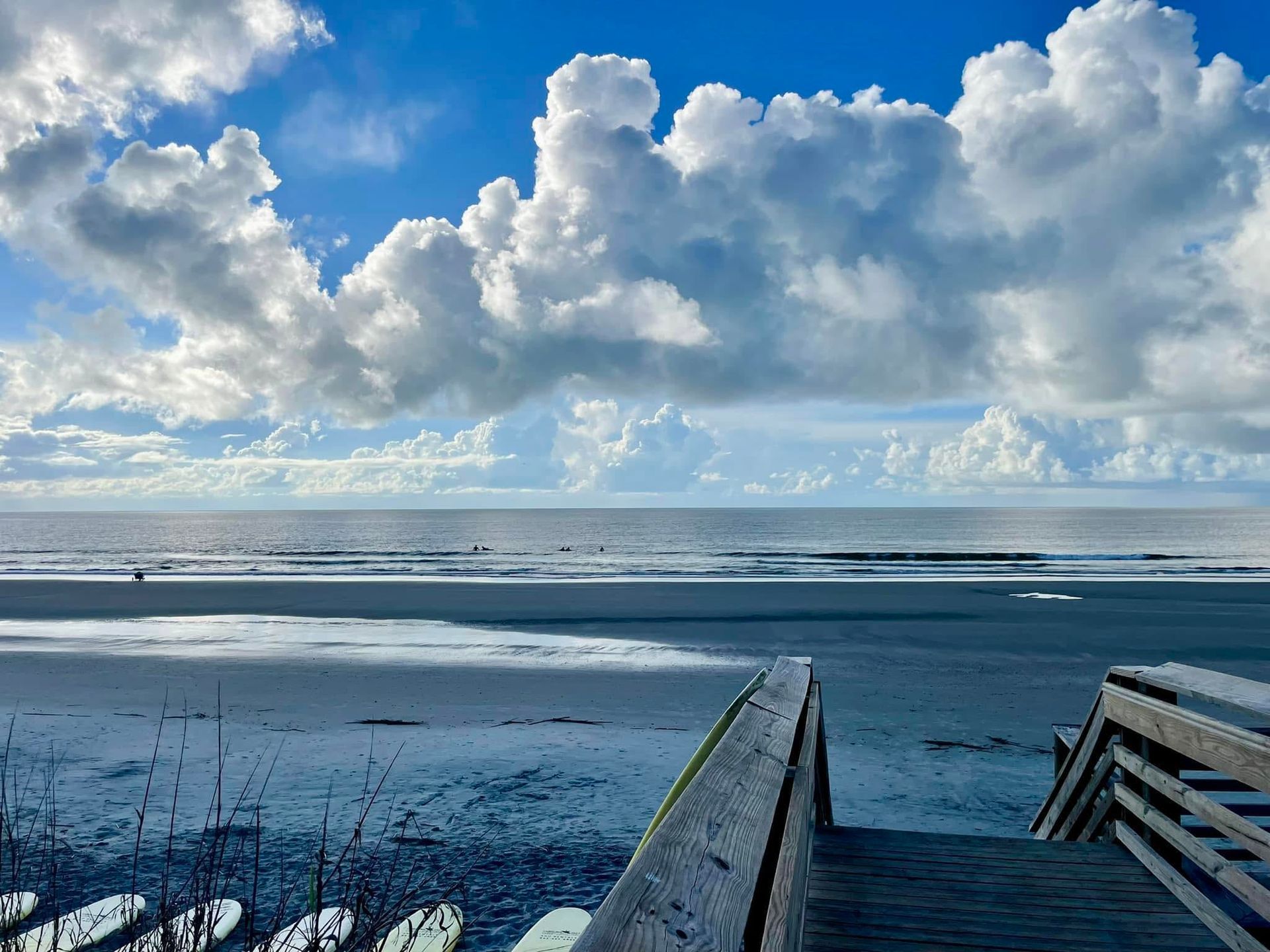 Wooden boardwalk leading to a snowy beach under a dramatic cloudy sky