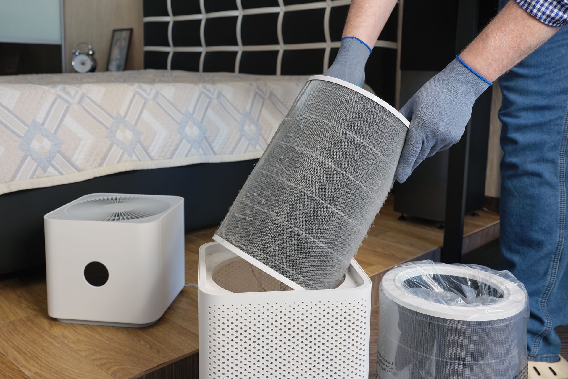 Hands replacing a cylindrical air filter on a tabletop air purifier indoors