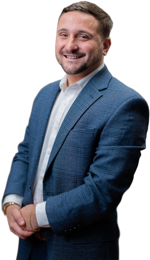 A woman wearing a sweater and a heart necklace is smiling at the camera.