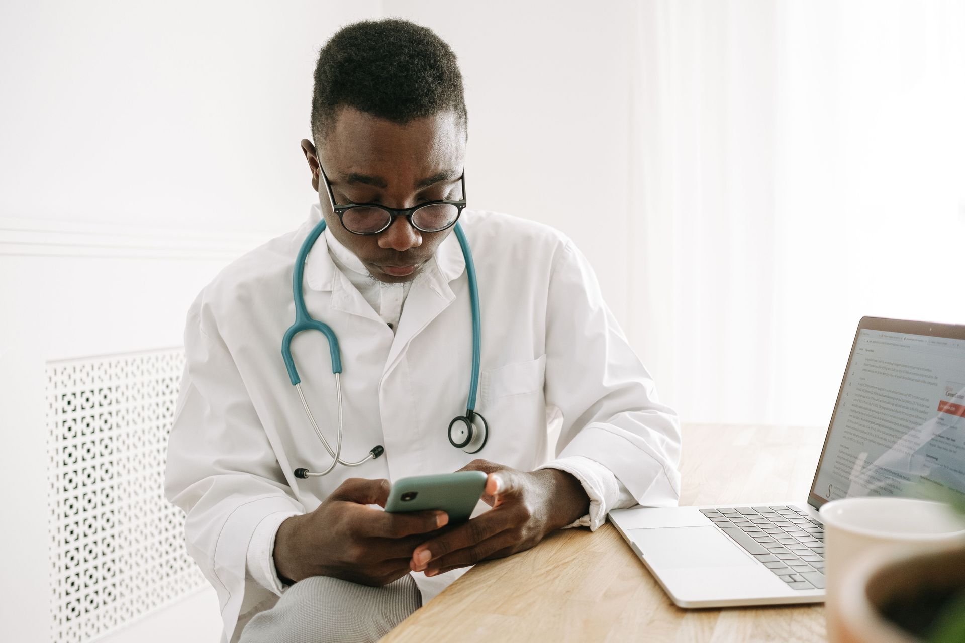 Physician in a white coat checking his practice's social media on a smartphone
