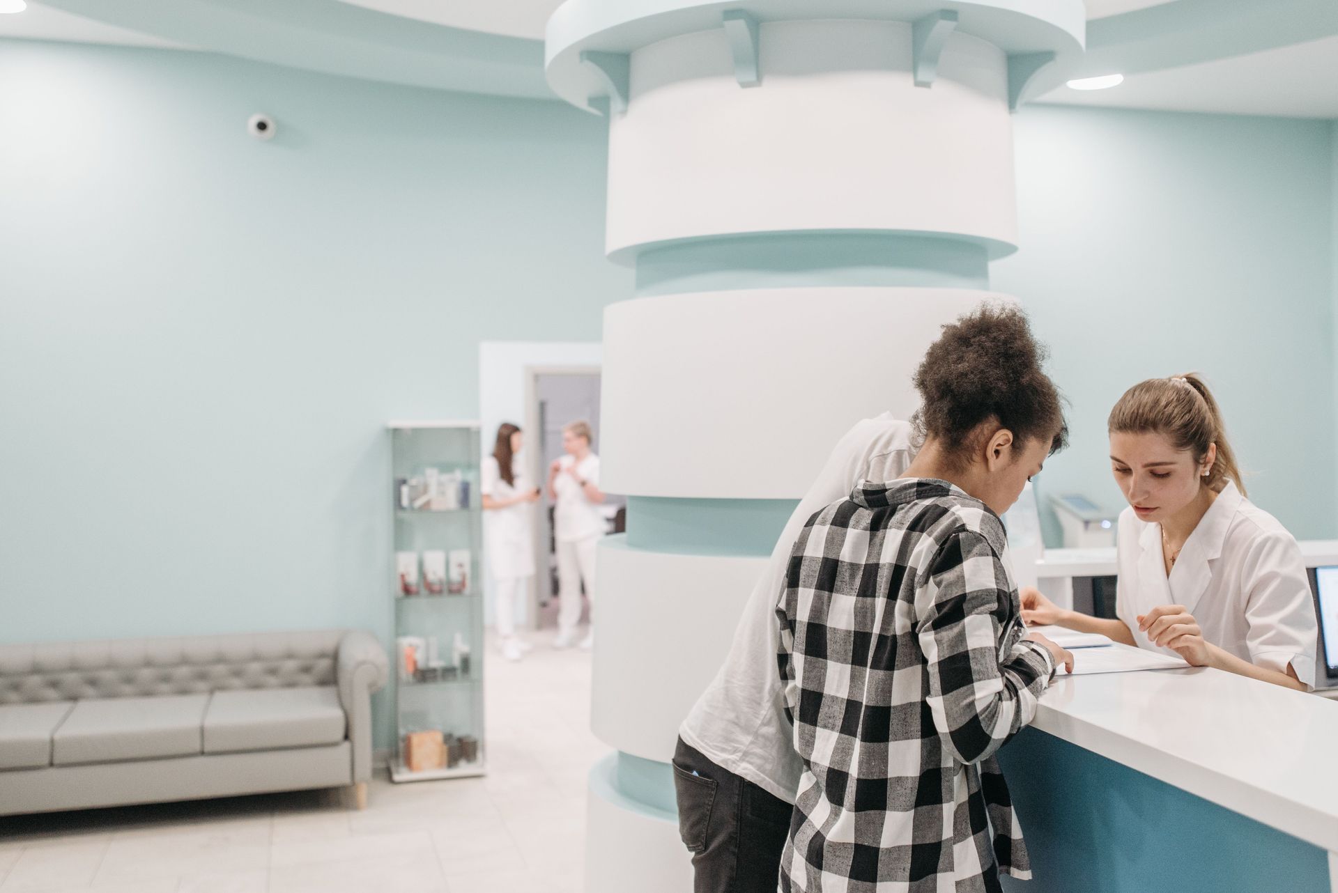 Medical front desk staff member checking in a patient at a clinic reception counter