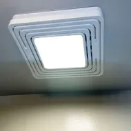 Square ceiling light with concentric white trim panels on a gray ceiling