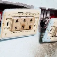 Damaged electrical wall outlets with exposed wiring and burnt, discolored sockets
