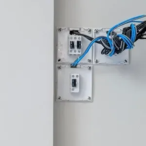 Wall-mounted electrical boxes with blue network cables and switches on a white wall