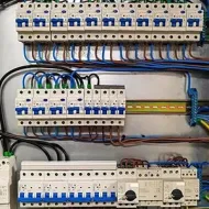 Electrical breaker panel with rows of white circuit breakers and neatly routed blue and black wires