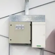 Wall-mounted electrical breaker panels with gray and white metal boxes and three switches.