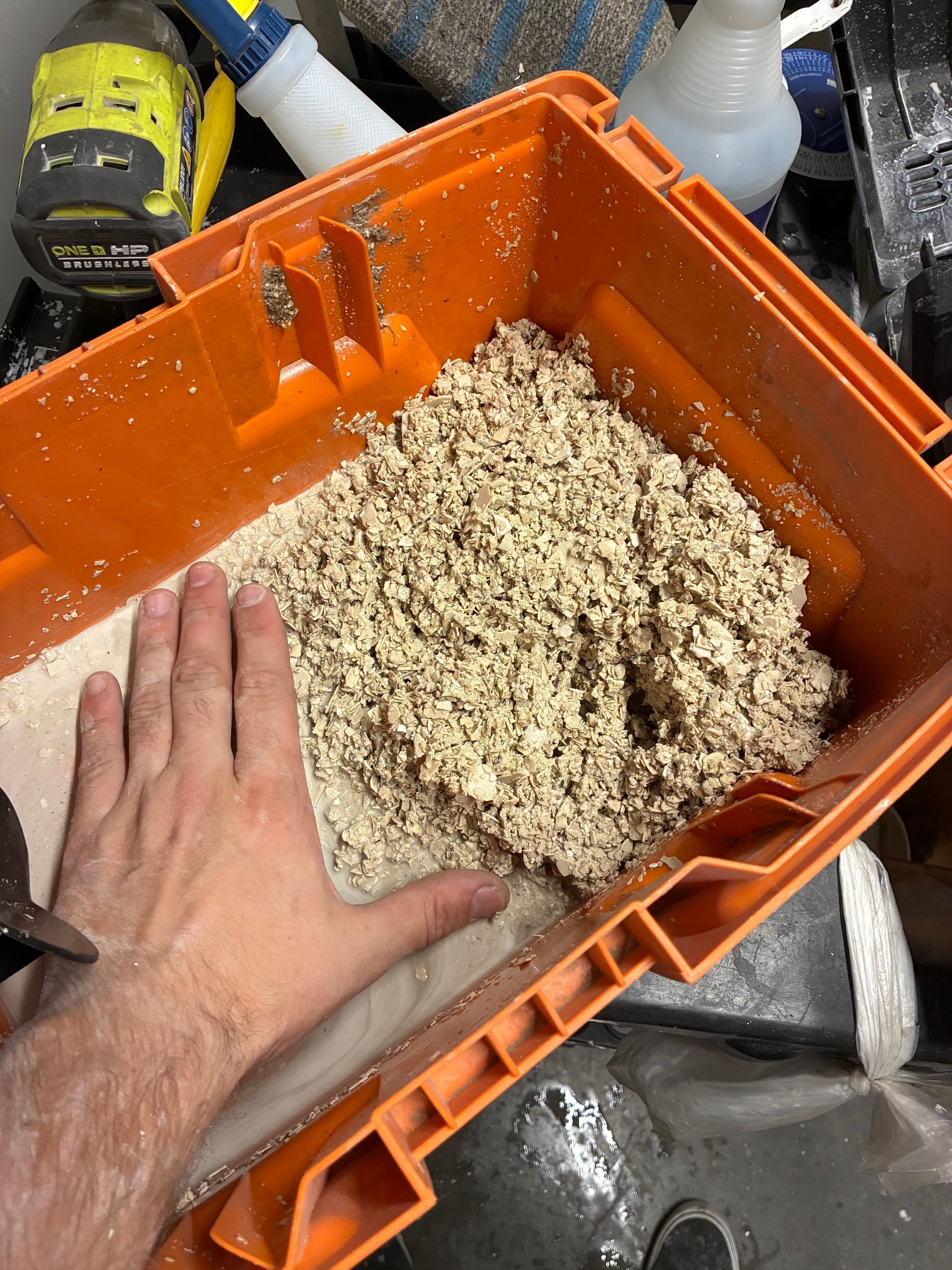 A person is holding a box of sand in their hand.