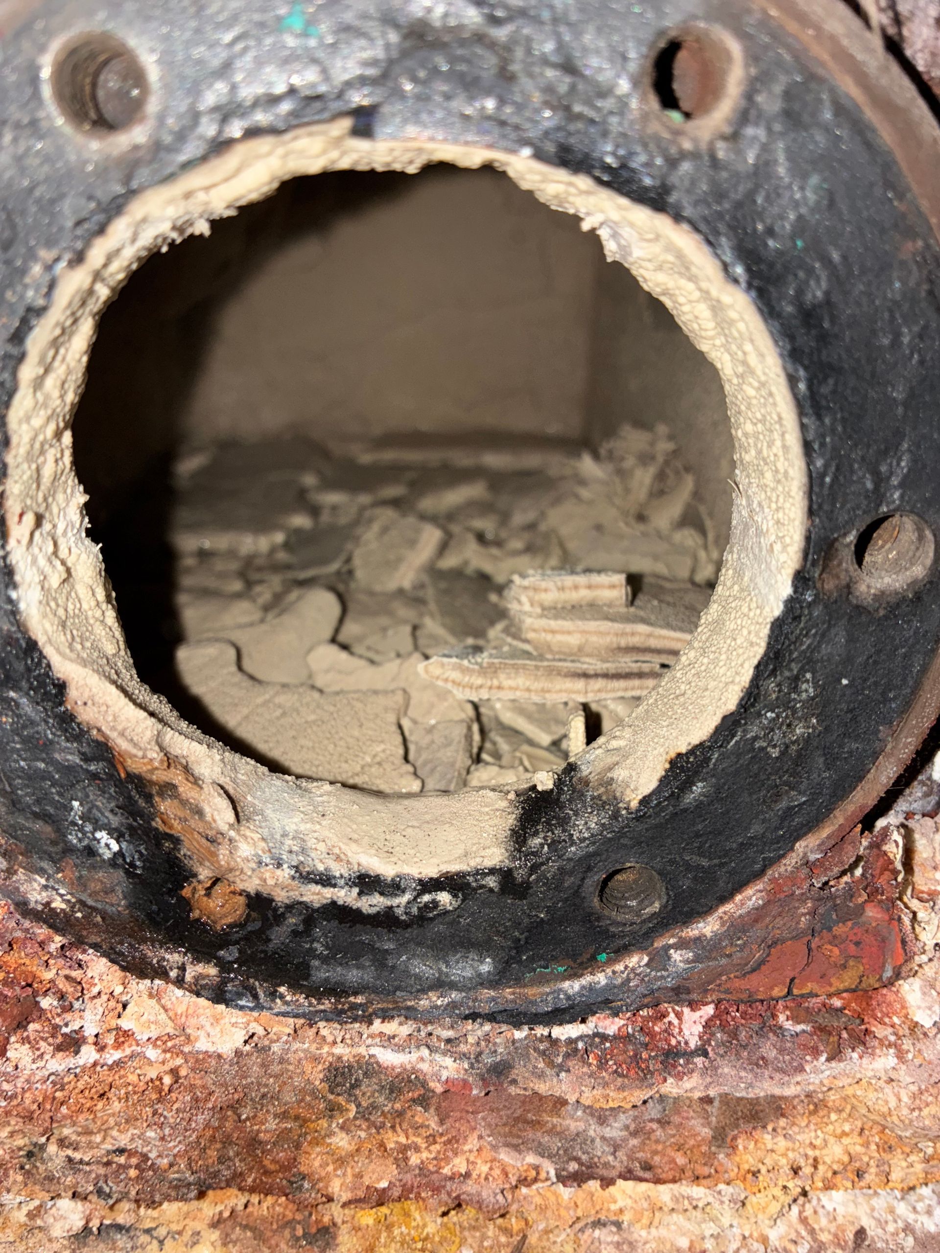A close up of a rusty pipe with a hole in it.