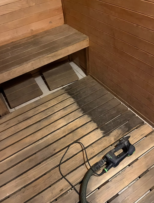 A vacuum cleaner is sitting on a wooden floor in a sauna.