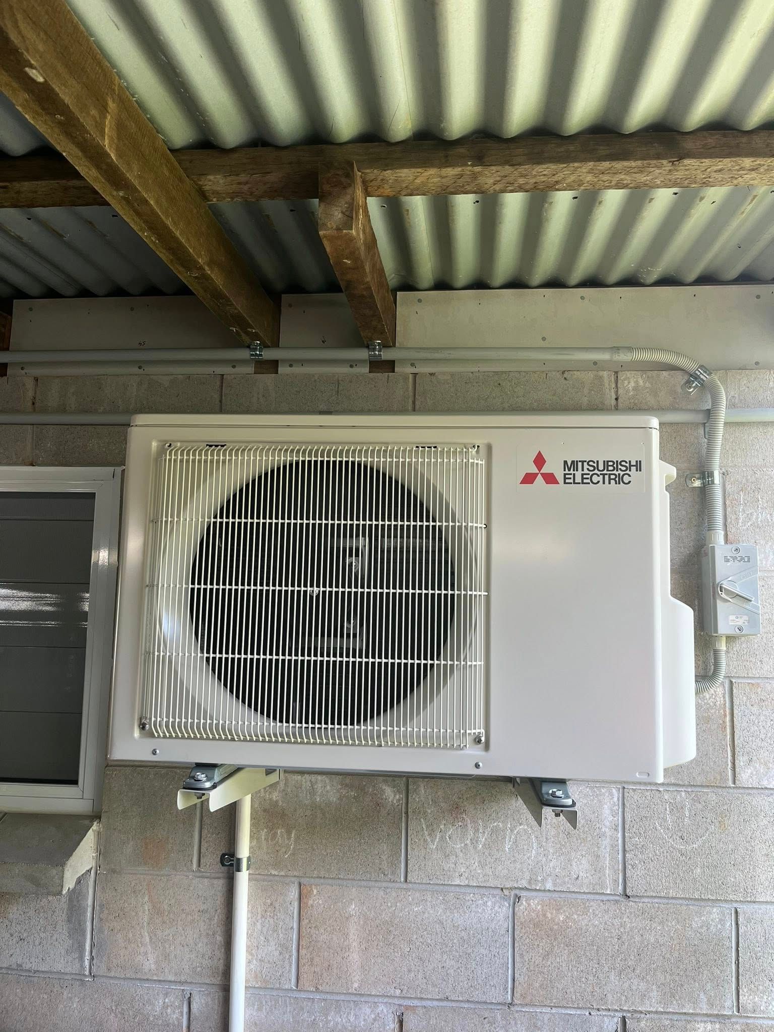 Outdoor Air Conditioner Unit Beside a Sunlit Window on a Tiled Balcony — Top Spark Electrical FNQ in Mareeba, QLD