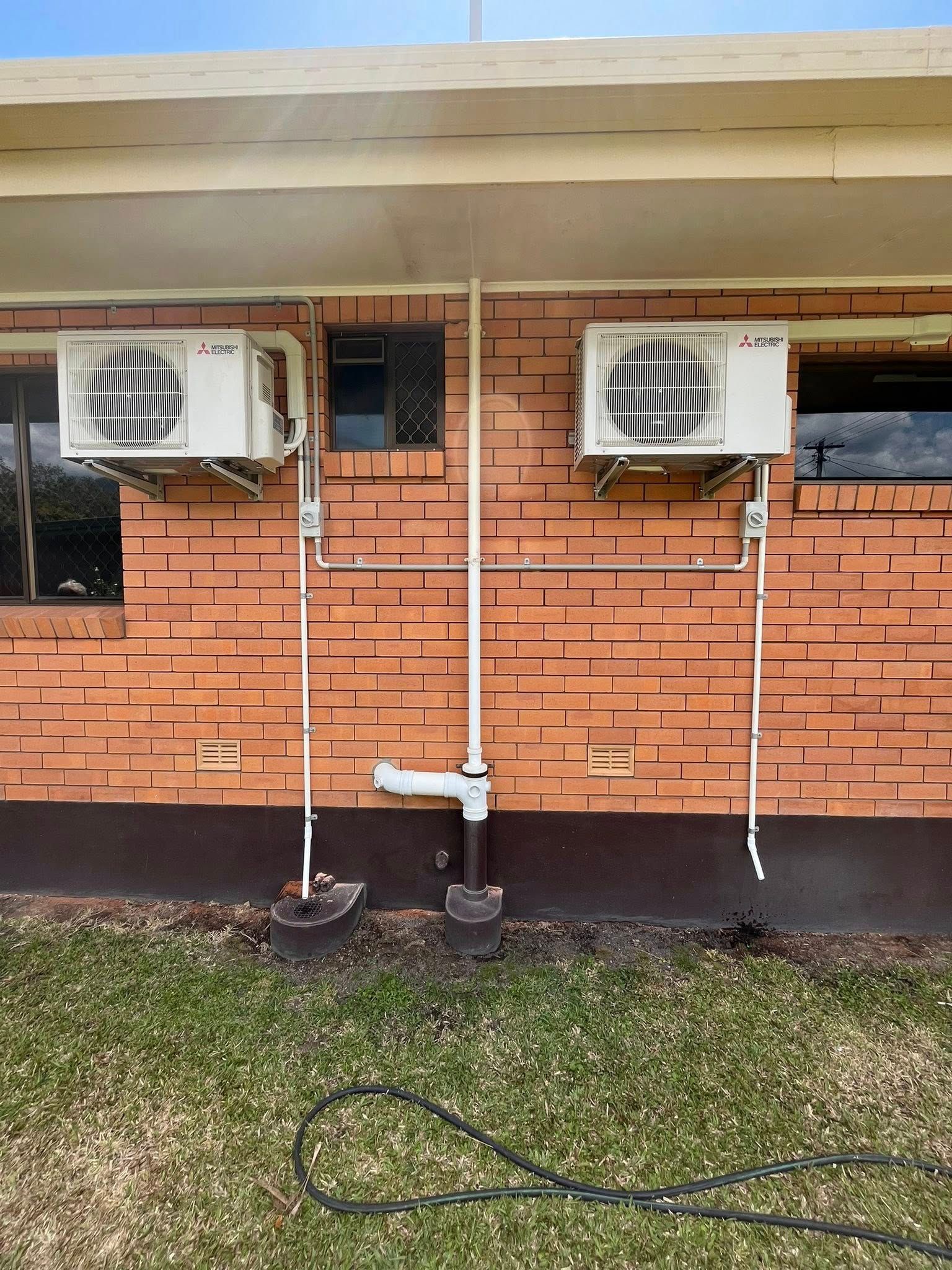 Two Wall-mounted Air Conditioners With Exposed White Pipes — Top Spark Electrical FNQ in Mission Beach, QLD