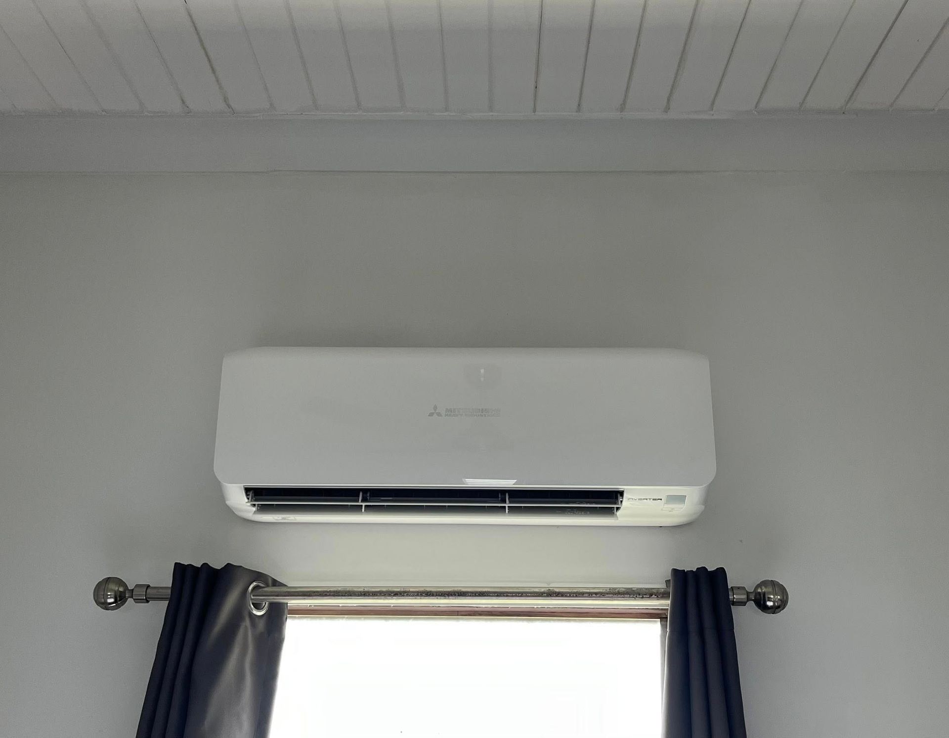 White Wall-mounted Air Conditioner Above a Window — Top Spark Electrical FNQ in Malanda, QLD