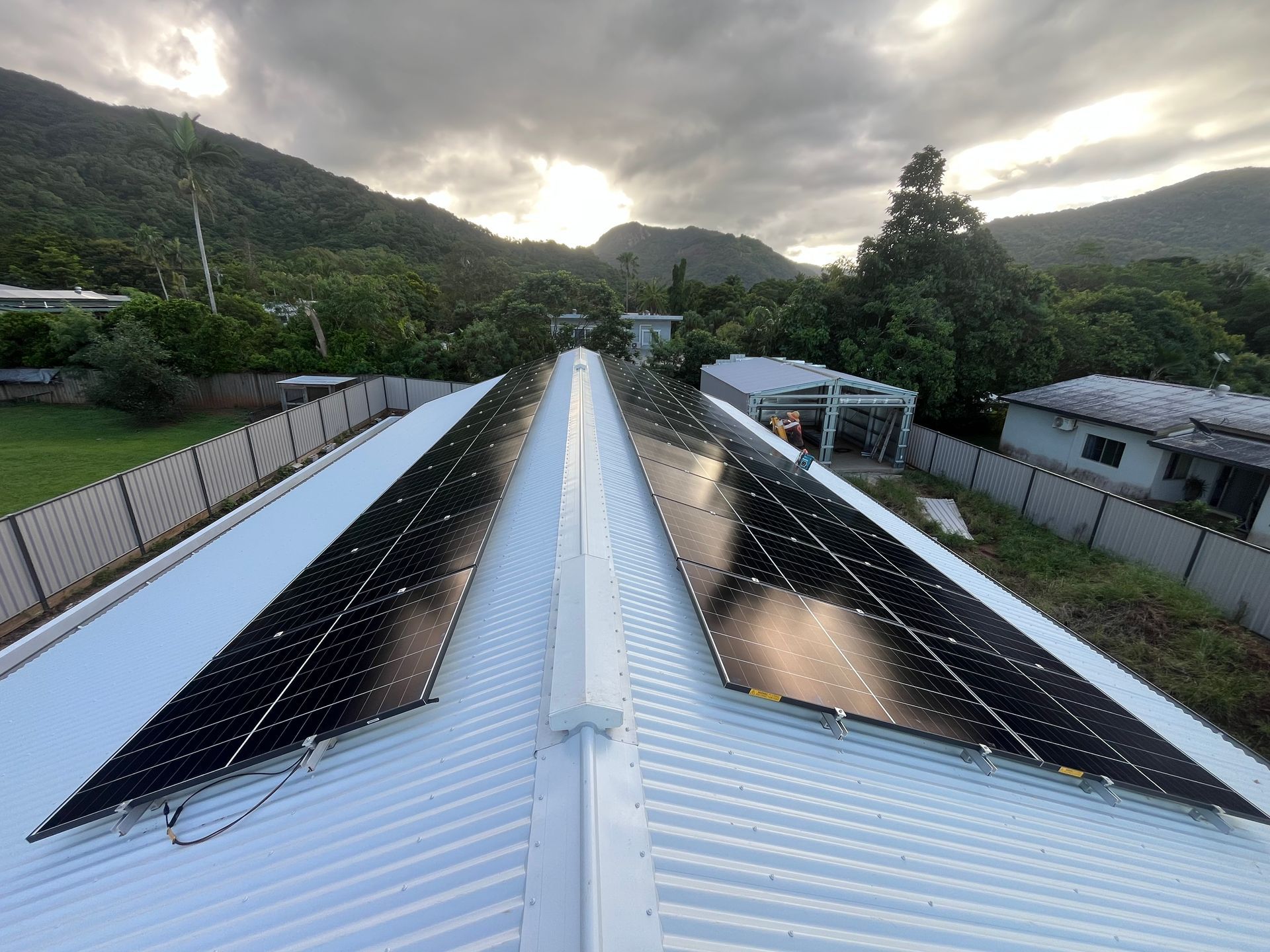 Solar Panels Mounted on a Metal Roof Beside a Green Hillside — Top Spark Electrical FNQ in Mission Beach, QLD