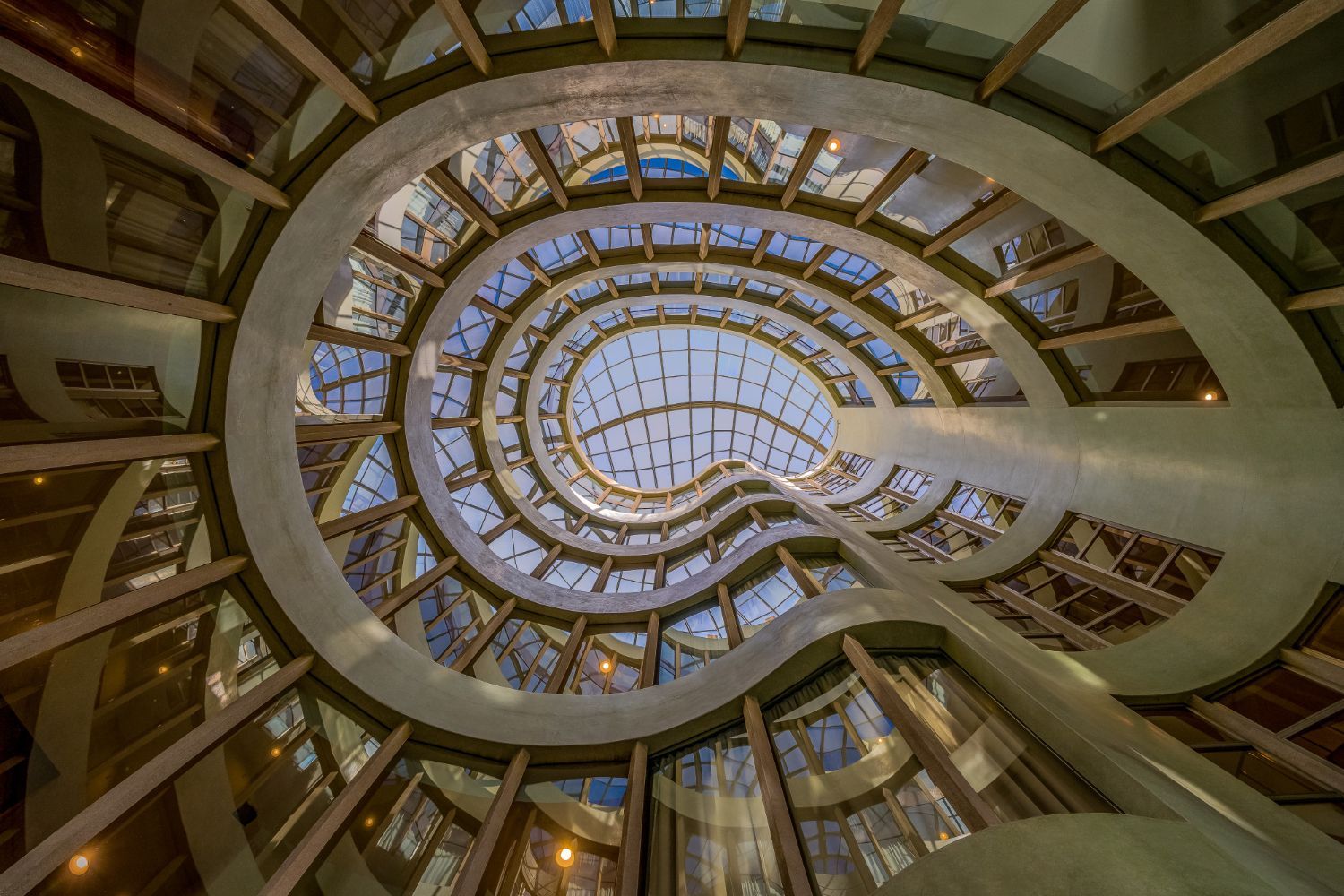 Blick nach oben auf eine Wendeltreppe mit Buntglasfenstern.