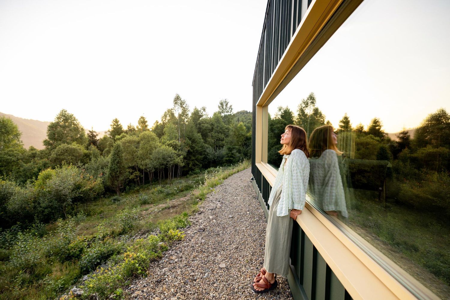 Eine Frau schaut aus einem Fenster auf einen Wald.